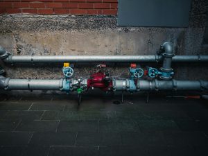 Industrial pipes with colorful valves against a wall